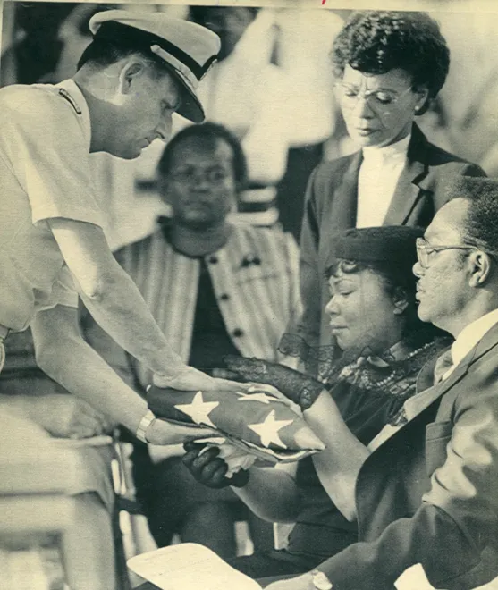 29 May 1987: RADM Stanley E. Bump presents an American flag to Georgia and Melvin Daniels, the family of Antonio Daniels, at services in 
                            Florence, SC, National Cemetery.