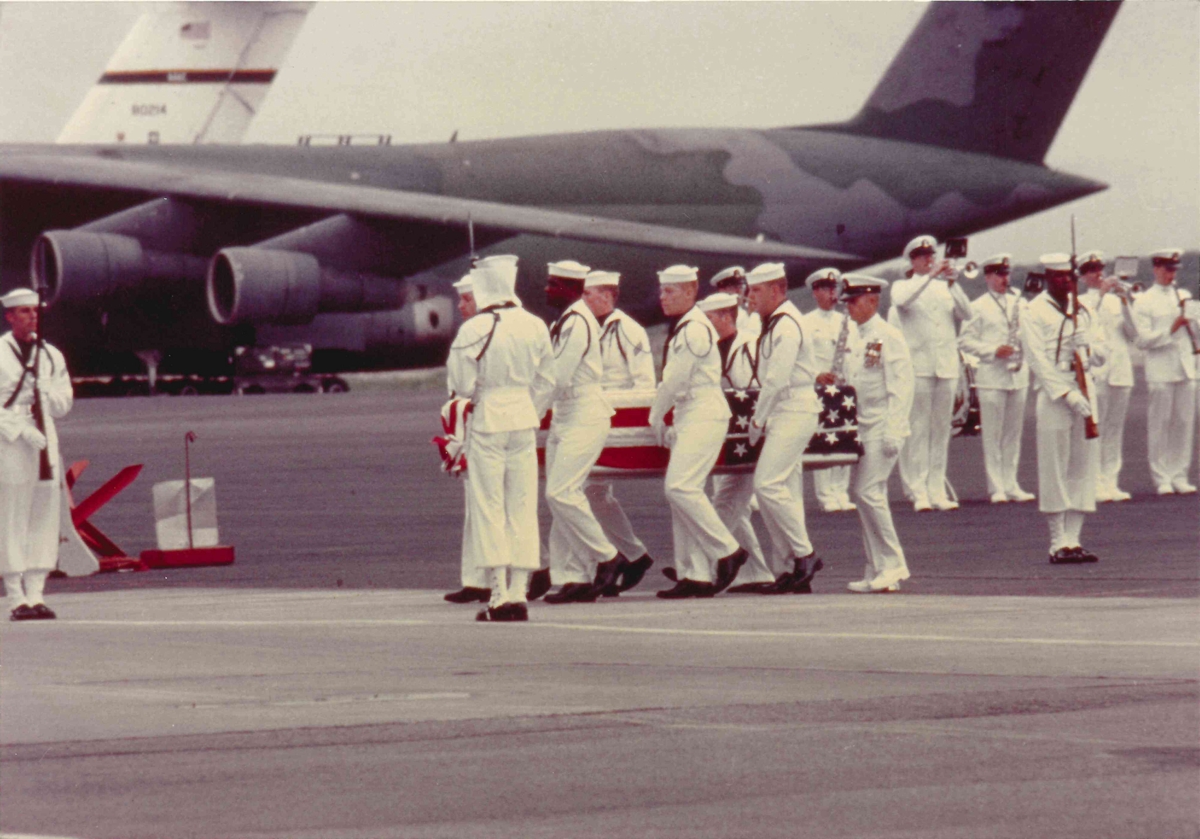 Honor Guard carrying one of the flag-draped coffins.